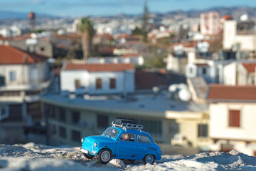 Miniature blue car exploring a blurred cityscape