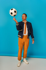 Young man in vibrant clothes skillfully balances a soccer ball against a colorful backdrop