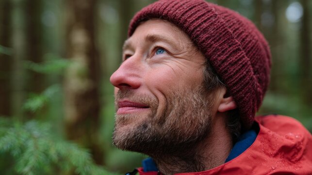 Man in red jacket smiling in forest.