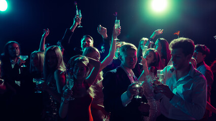 New Year party toast with champagne glasses under neon lights. Concept of alcohol brand promotion, nightlife energy, celebration culture, and emotional unity