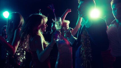 Joyful Christmas night with friends dancing and clinking glasses. Concept of holiday campaign visuals, event marketing, party fashion, and youth energy