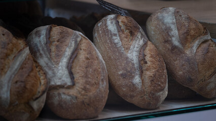 Artisan loaves of bread on bakery shelf with natural texture and crust. The image highlights the trend of craft baking and authentic food photography