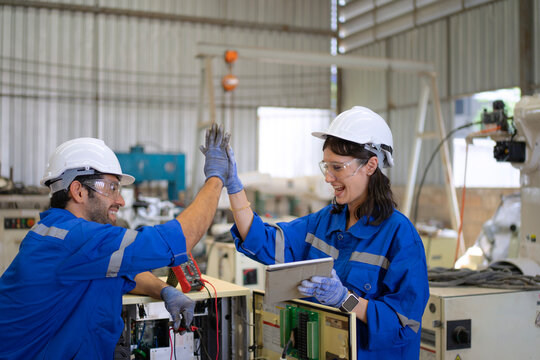 Blue collar workers at machine shop with welding robot arm.