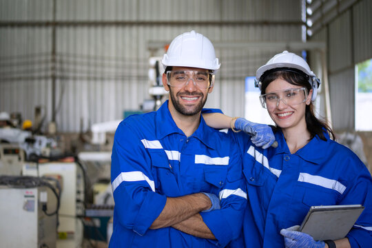 Blue collar workers at machine shop with welding robot arm.
