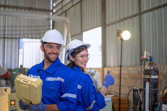 Blue collar workers at machine shop with welding robot arm. - Powered by Adobe
