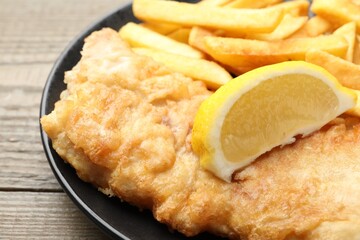 British Traditional Fish and chips served with lemon on wooden table, closeup