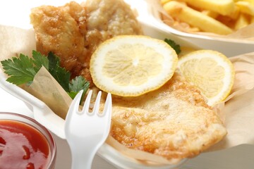 British Traditional Fish and chips served with sauce on table, closeup