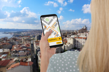 Naklejka premium Woman using app on mobile phone to call taxi outdoors, closeup