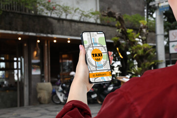 Woman using app on mobile phone to call taxi on city street, closeup © New Africa