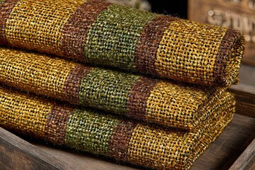 Stack of earthy-toned, textured woven fabric on rustic wood