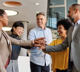 Portrait of a group of business people holding hands together in the office. Teamwork and success...