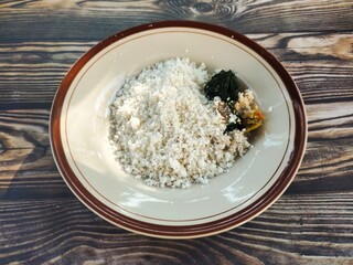 A plate of traditional Indonesian white corn rice, served with anchovies, boiled fennel leaves, and fresh spicy sambal.