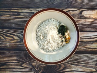 A plate of traditional Indonesian white corn rice, served with anchovies, boiled fennel leaves, and fresh spicy sambal.
