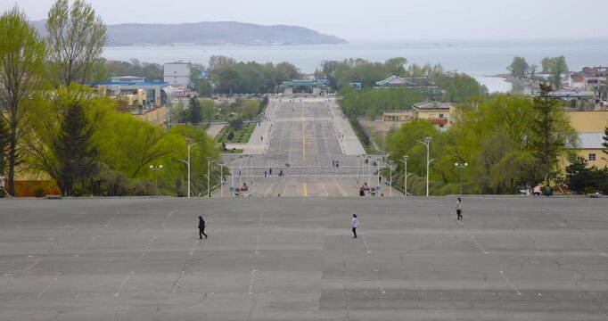 May 8, 2025 - Rason, North Korea - A street in a North Korean border town. Cars and people are moving along a deserted street.