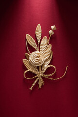Decoration of straw on a red background. Branch with flowers. Boutonniere made out of straw. Brooch. Straw weaving.