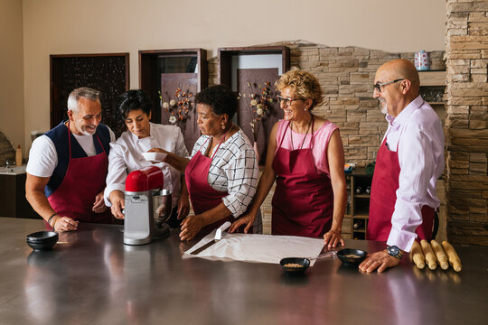 Chefs adding ingredients into stand mixer during cooking class