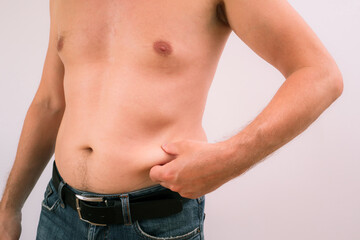 Naklejka premium Man Pinching Belly Fat. Close-up of a man's abdomen.