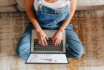 Top view of woman analyzing data on laptop while working at home