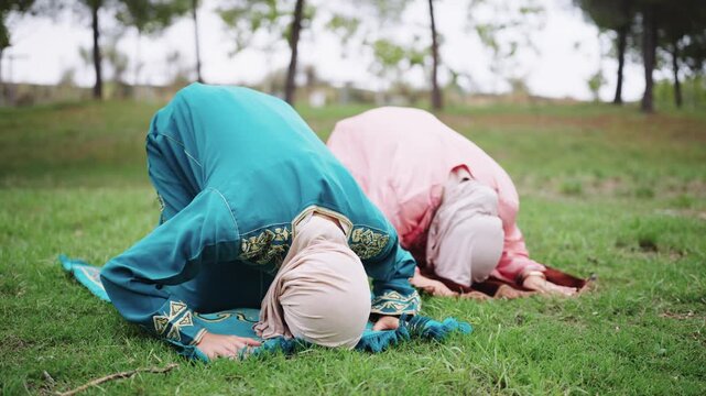 Muslim women performing islamic prayer salah in a park