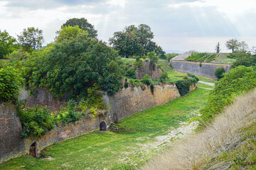 Fortified grass-covered walls of Hornwerk section in Petrovaradin Fortress. Symbol of nature reclaiming heritage, historical defense line, forgotten architecture, and exploring abandoned places.