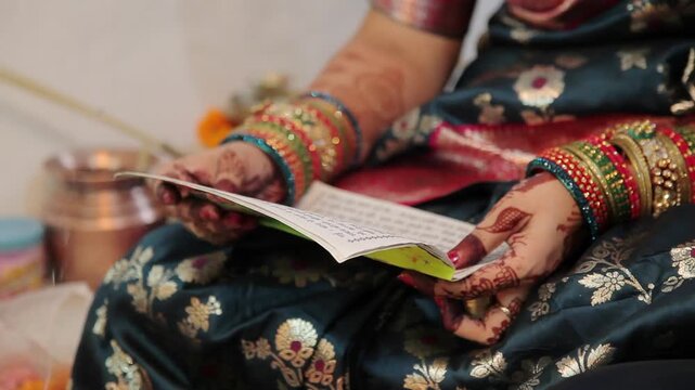 An Indian woman in a blue saree reading a book during a cultural festival celebration