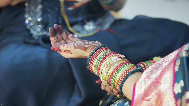 An Indian woman in a blue saree, tying sacred kalawa thread on another woman&rsquo;s wrist during a Hindu festival