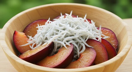 Close up of plum slices and small fish on wooden bowl