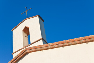 Old italian little church with metal Christian cross on the top against a sky - concept image with copy space
