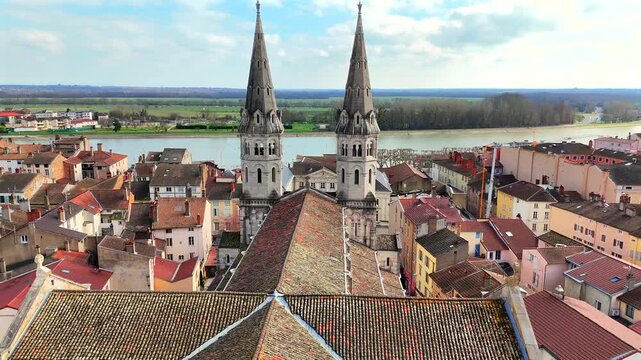 Twin spire church and tiled roofs near river in Macon