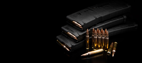 A low-key banner of rifle magazines and brass cartridges on a glossy black back