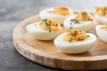 Homemade hard Boiled Deviled Eggs garnished with herbs on wooden table