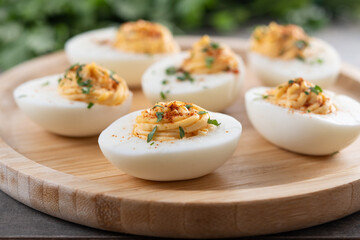 Homemade hard Boiled Deviled Eggs garnished with herbs on wooden table
