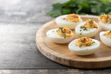 Homemade hard Boiled Deviled Eggs garnished with herbs on wooden table. Copy space