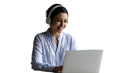 Young Indian woman with headphones smiles working on laptop at home desk. Engaging in online education, business, communication. Student learning lesson, attending virtual meeting class