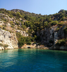Obraz premium Clear blue waters surround rocky cliffs and lush greenery in a serene coastal landscape