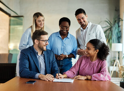 Group of young and senior business people having a meeting and signing a contract agreement in the office. Teamwork and success concept