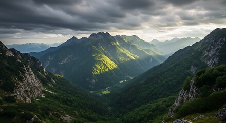 Dramatic mountain landscape under a stormy sky with bright sunlight illuminating peaks