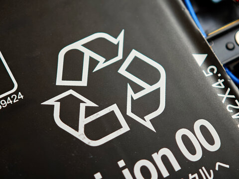Recycling symbol on a lithium-ion laptop battery close up three chasing arrows on black label recyclability proper e-waste handling hazardous li-ion cells abstract concept sustainability safe disposal