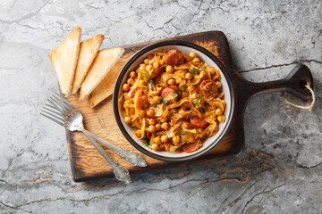 Spanish vegetable stew with cabbage, chickpeas, chorizo ​​and paprika close-up in a plate on the table. Horizontal top view from above