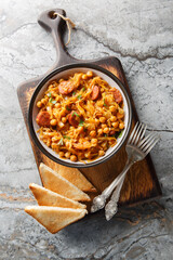 Spanish traditional cabbage chickpea stew with paprika and sausages close-up in a plate on the...