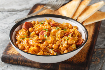 Spanish traditional cabbage chickpea stew with paprika and sausages close-up in a plate on the table. Horizontal