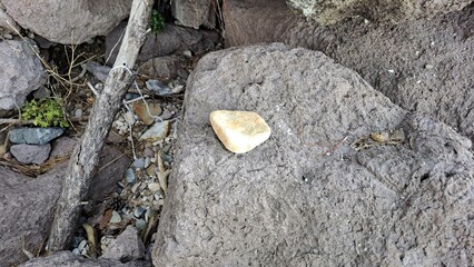 a smooth, pale yellow pebble resting on a large, rough grey boulder