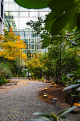 Modern Office Building With Autumn Garden Pathway: Contemporary Glass Architecture Surrounded By Colorful Trees And Soft Evening Lights In Urban Setting