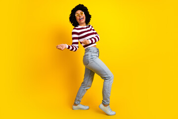 Smiling young woman with casual attire posing against vibrant yellow backdrop exuding joy and confidence while standing