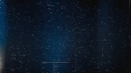 Dark blue grunge texture background with white dust, scratches, and film grain. Perfect for vintage photography effects, cinematic overlays, retro designs, and distressed backdrops.