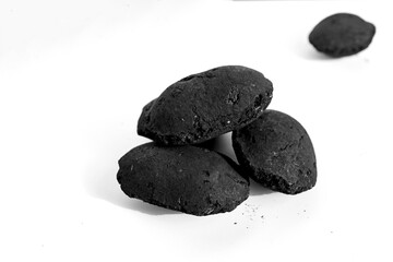 Fototapeta premium dark, pillow-shaped charcoal briquettes arranged on a white background, symbolizing barbecue fuel, outdoor grilling, and carbon energy sources for cooking, leisure, and heating concepts