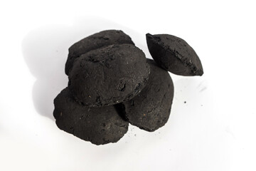 round black charcoal briquette isolated with a subtle shadow on a clean white background, representing processed barbecue fuel, compressed carbon energy, and outdoor grilling material for leisure and 