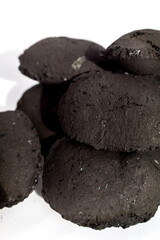 black charcoal briquettes stacked on a pure white surface with a soft shadow: Represents barbecue fuel, cooking energy, simple product focus, and outdoor grilling preparation