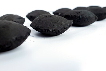 Charcoal briquettes arranged on a white background, showing rough black surface texture. Ideal for energy, barbecue, eco fuel, or industrial heating concepts in product photography