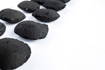 Charcoal briquettes arranged on a white background, showing rough black surface texture. Ideal for energy, barbecue, eco fuel, or industrial heating concepts in product photography